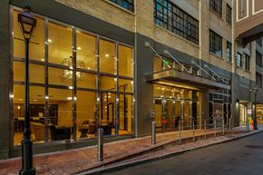 New Orleans apartment for rent - A building with a glass facade and a black lamp post in front.
