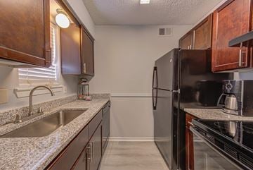 Baton Rouge townhouse for rent - A kitchen with a black refrigerator and brown cabinets.