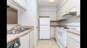 Shreveport apartment for rent - A white refrigerator is in the middle of a kitchen with white cabinets and a white stove.