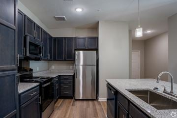 Shreveport apartment for rent - A kitchen with dark wood cabinets and stainless steel appliances.