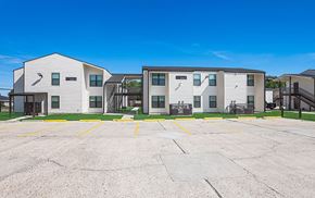 New Orleans townhouse for rent - A parking lot in front of a building with a clear blue sky.