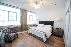 New Orleans apartment for rent - A bedroom with a large bed and a chair in front of a window.