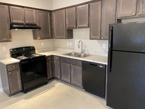 Bastrop apartment for rent - an empty kitchen with black appliances and wooden cabinets