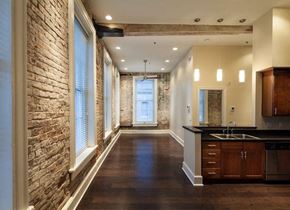 New Orleans apartment for rent - A long hallway with a brick wall on the left and a kitchen area on the right.
