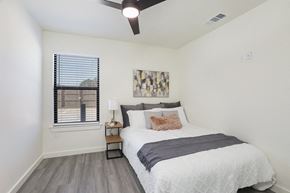 Baton Rouge townhouse for rent - A bedroom with a bed, a ceiling fan, and a window with blinds.
