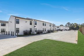 Baton Rouge townhouse for rent - A row of white houses with a green lawn in front.