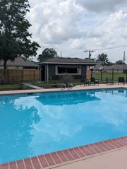 Baton Rouge apartment for rent - A pool with a red brick border and a house in the background.