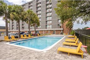 New Orleans apartment for rent - A pool area with yellow sun loungers and a tall building in the background.