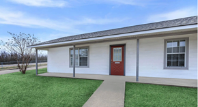 Shreveport apartment for rent - A small white house with a red door and a brown walkway leading to it.