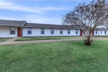 Shreveport apartment for rent - A white building with a red door and a tree in front.