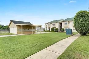 Shreveport apartment for rent - A row of houses with a green lawn in front.