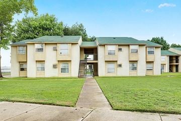 Shreveport apartment for rent - A building with a green roof and beige walls with a staircase leading to the entrance.