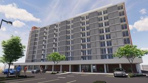 New Orleans apartment for rent - A modern building with a large glass facade and a parking lot in front.