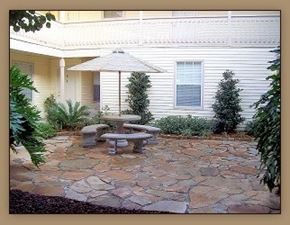 Slidell apartment for rent - A patio with a table and chairs is surrounded by plants.