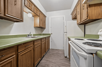 Shreveport apartment for rent - A kitchen with wooden cabinets and a white stove top oven.