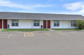 Shreveport apartment for rent - A white building with red doors and windows is surrounded by a parking lot.