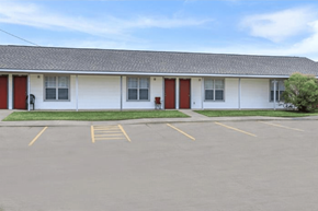 Shreveport apartment for rent - A white building with red doors and windows is surrounded by a parking lot.