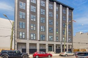 Philadelphia apartment for rent - A tall building with a grey facade and a row of cars parked in front.