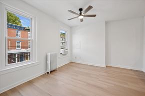Philadelphia apartment for rent - A room with a ceiling fan and a window overlooking a building.