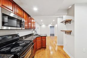 Philadelphia apartment for rent - a kitchen with wood flooring and black appliances and wooden cabinets
