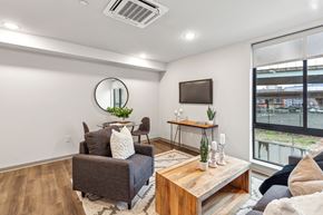 Philadelphia apartment for rent - A living room with a grey couch, a wooden coffee table, and a round mirror on the wall.