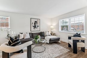 Flourtown apartment for rent - A living room with a grey couch, a white chair, and a black and white striped pillow.