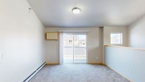 West Fargo apartment for rent - A spacious empty room with a sliding glass door leading to a balcony.