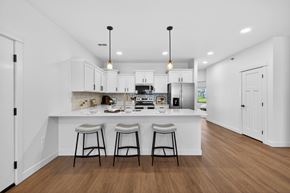 Fargo townhouse for rent - A kitchen with white cabinets and a white island with two stools.