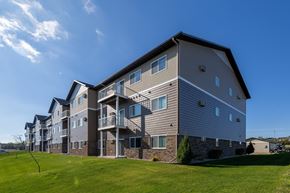 Mandan apartment for rent - A large apartment building with a grassy area in front.
