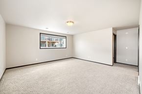 Fargo townhouse for rent - A spacious room with a framed picture on the wall and a carpeted floor.
