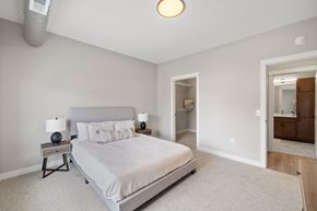 Fargo townhouse for rent - A bedroom with a large bed and a nightstand with a lamp.