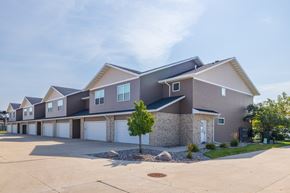 West Fargo townhouse for rent - A large, modern house with a grey and brown exterior and a white garage door.