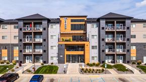 Fargo apartment for rent - A large apartment complex with a central building entrance and cars parked in the driveway.