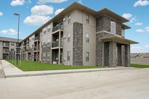 Watford City apartment for rent - an apartment building with a sidewalk and grass