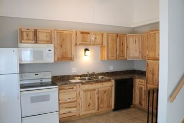 West Fargo triplex for rent - A kitchen with wooden cabinets and a black dishwasher.