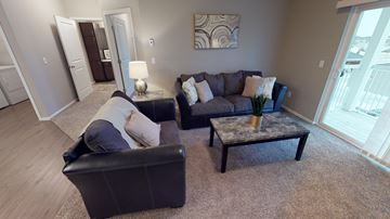 Moorhead apartment for rent - A living room with a black couch, a coffee table, and a painting on the wall.