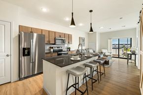 West Fargo apartment for rent - a kitchen with a large island and a stainless steel refrigerator at The Standard on 32nd, West Fargo, North Dakota