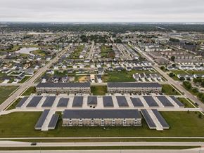 Moorhead apartment for rent - A large building complex with a parking lot in front.