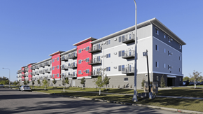 Fargo apartment for rent - A street view of a multi-story building with red and grey sections.