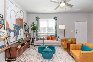 Waco apartment for rent - A living room with a white couch, a brown chair, and a painting on the wall.
