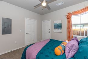 Waco apartment for rent - A bedroom with a bed covered in a teal and pink comforter and two orange and purple pillows.