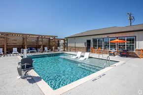 Tyler apartment for rent - A pool with chairs around it and a building in the background.