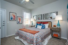 Tyler apartment for rent - A bedroom with a bed, nightstand, and a ceiling fan.