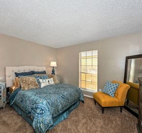Dallas apartment for rent - a bedroom with a bed and a yellow chair