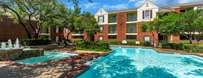 Dallas apartment for rent - a swimming pool with a fountain in front of an apartment building