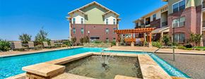 Lubbock apartment for rent - A large outdoor swimming pool with a fountain in the middle of it.