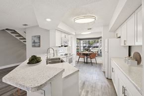 Orlando townhouse for rent - A modern kitchen with a marble countertop and a dining table with chairs.
