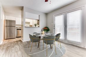 Richardson apartment for rent - a dining room with a table and chairs and a kitchen with stainless steel appliances at Falls on Clearwood Apartments, Richardson, TX, Texas
