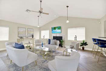 A living room with white furniture and a flat screen tv mounted on the wall.