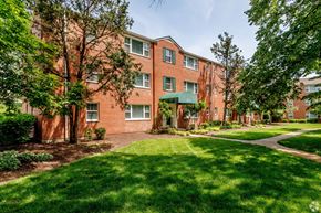 Saint Louis apartment for rent - exterior view of a brick apartment building with green grass and trees at Hampton Gardens, Missouri, 63139